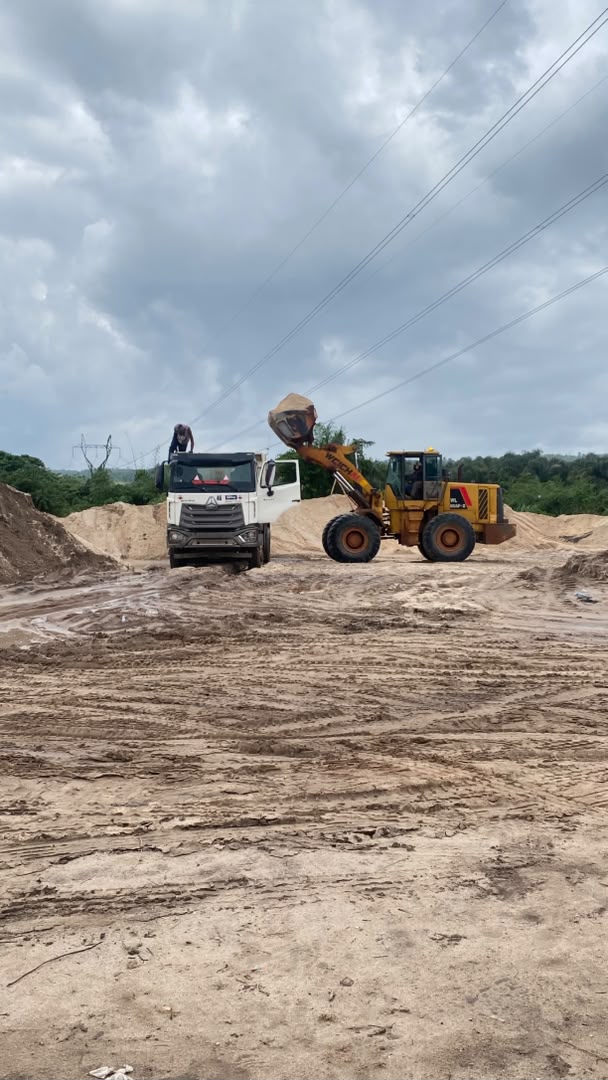 Loader and haul truck preparing sand for construction material delivery
